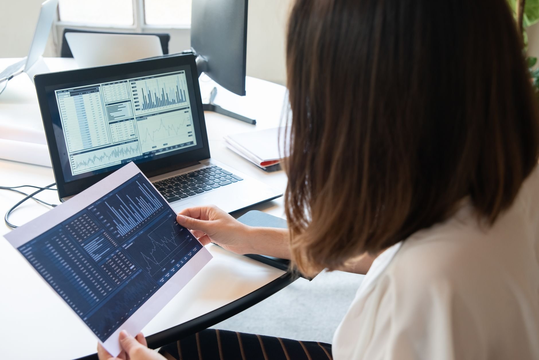A professional woman analyses financial charts on a laptop, representing informed investing.